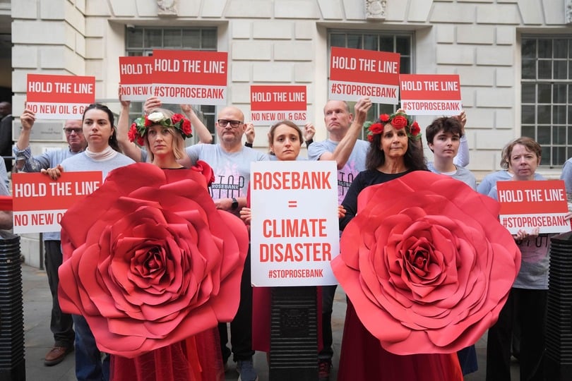 Organisers from Fossil Free London demonstrate using red ribbon to visually emphasise the Government’s legally binding commitment to the Paris Climate Agreement, as a decision on Jackdaw and Rosebank oil fields is awaited (PA)
