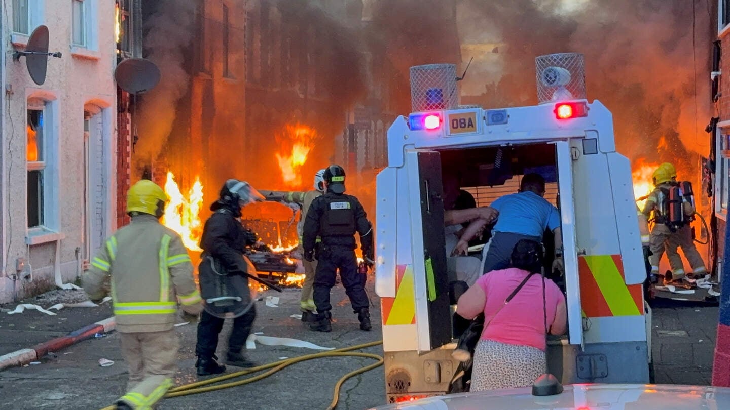 A family get into a PSNI vehicle after being rescued from houses which caught fire in Lendrick Street in east Belfast