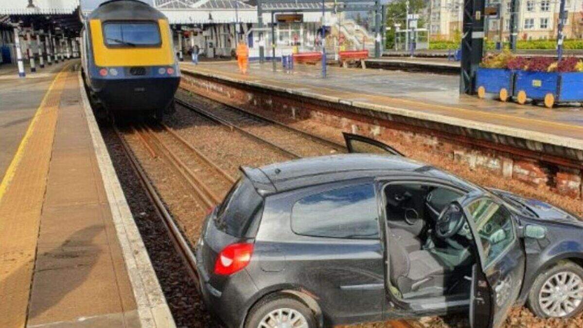 Two people in hospital after car lands on train tracks at station ...