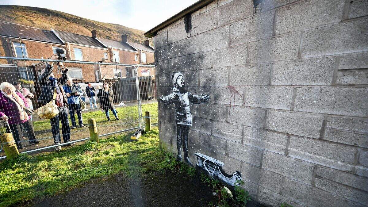 A Banksy mural of a child in winter clothing on a concrete wall
