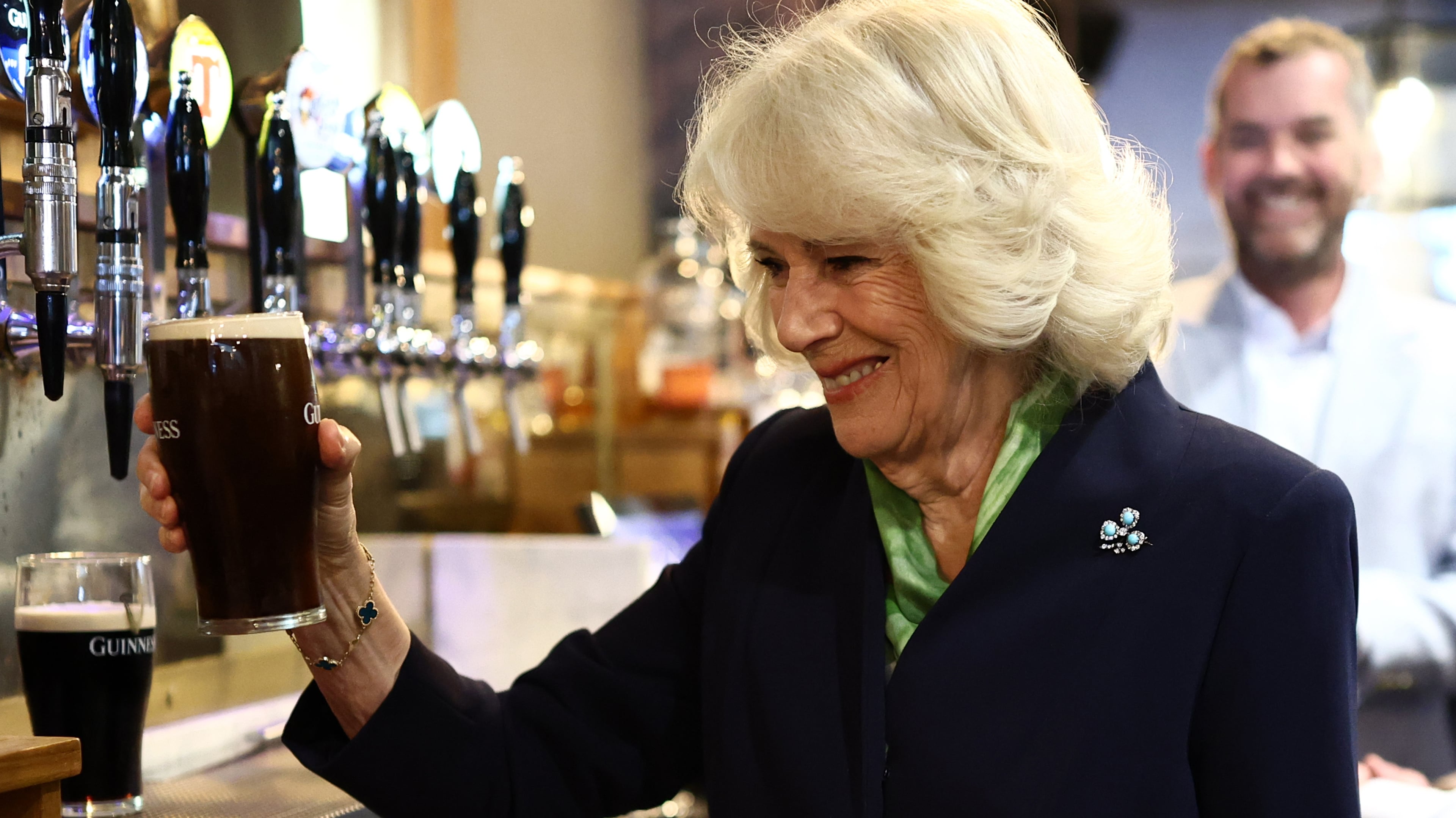Queen Camilla pours on the charm with a stop behind the bar in Hillsborough on day two of royal visit