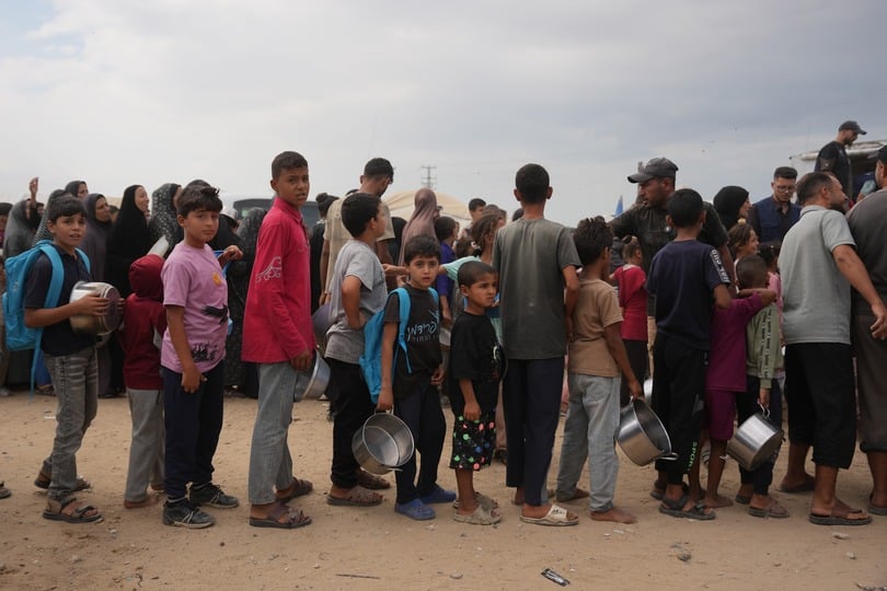 Palestinians line up to receive food donated by the World Food Programme at a displacement camp in Deir al-Balah, in central Gaza (Abdel Kareem Hana/AP)